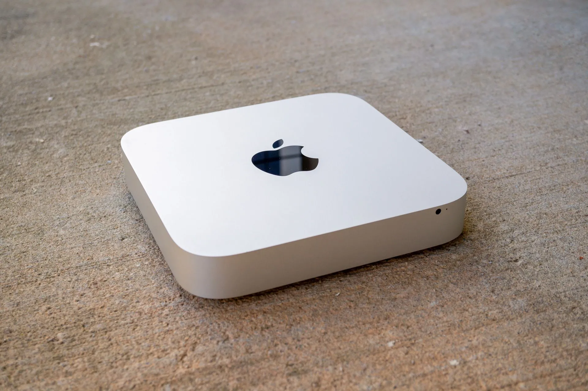 Apple Mac Mini (Late 2012) nhỏ gọn, đặt trên bề mặt bê tông, biểu tượng của sự linh hoạt.