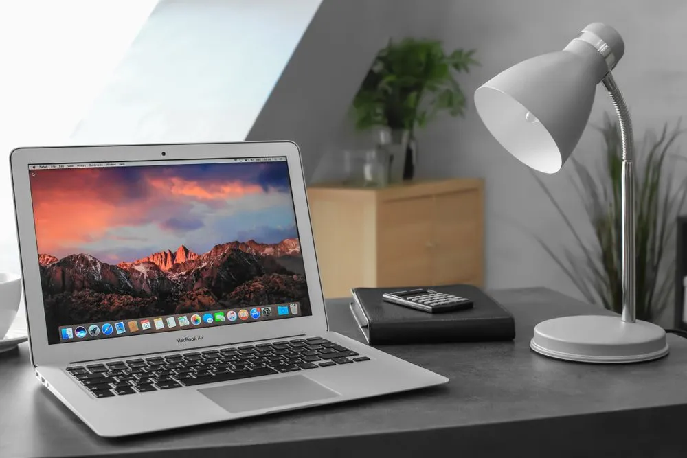 Apple MacBook Air Silver 2017 với màn hình desktop screensaver đặt trên bàn trong nhà.