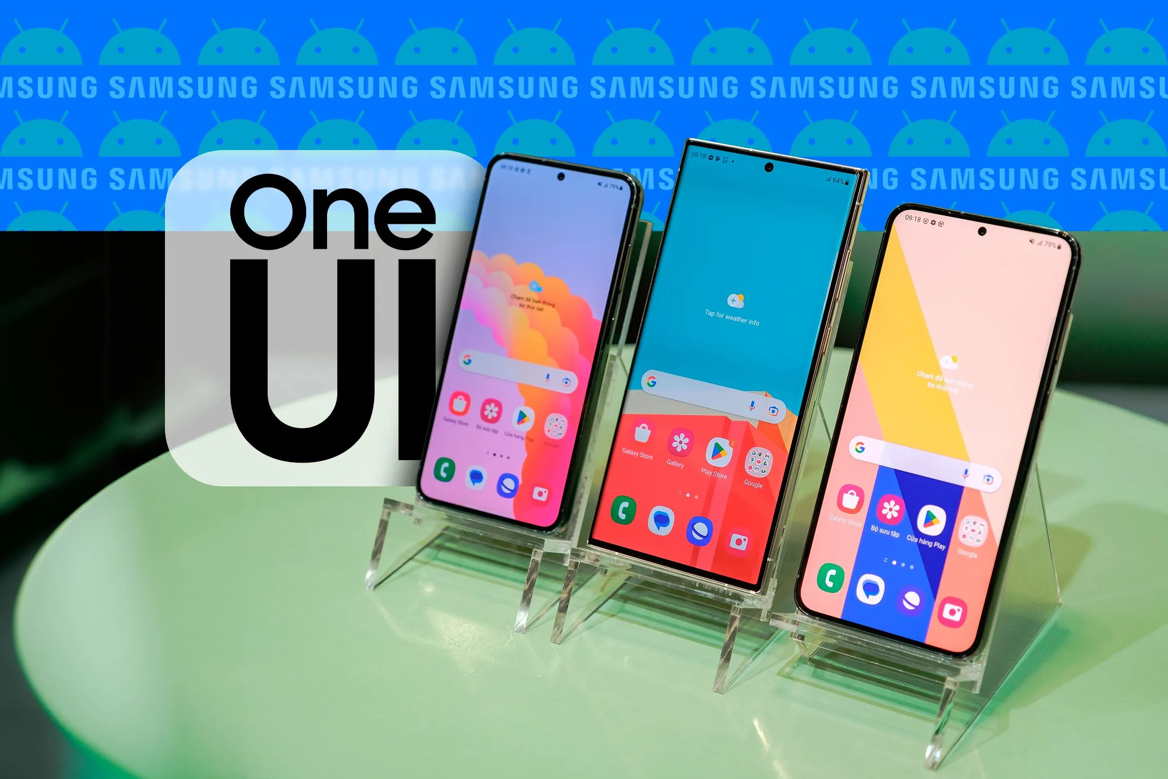 Ba chiếc điện thoại Samsung được đặt cạnh nhau, hiển thị giao diện One UI và logo One UI cùng logo Samsung và Android ở phía sau.