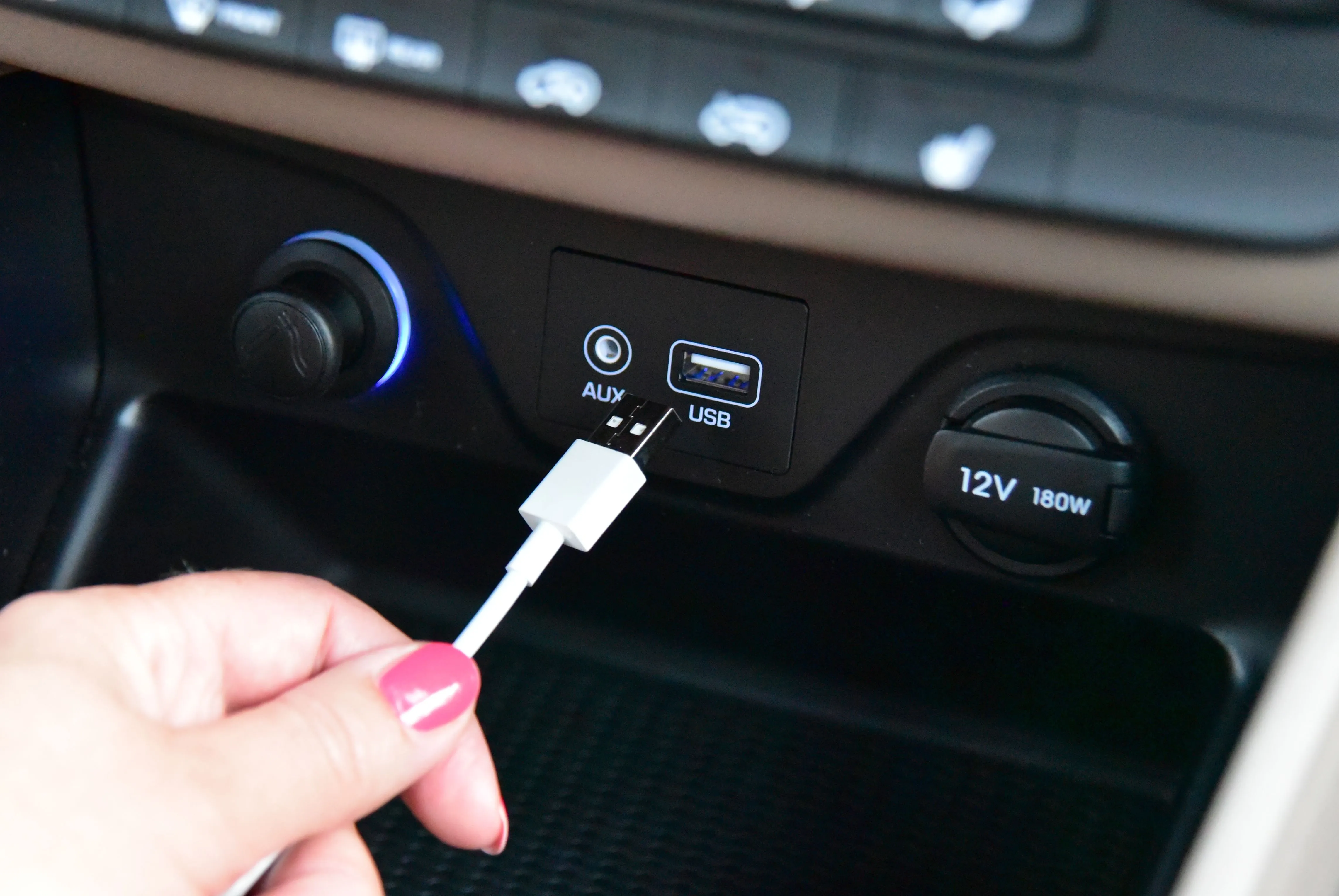 Bàn tay cắm cáp USB-A vào cổng trên bảng điều khiển ô tô, minh họa sự bất tiện của chuẩn cũ
