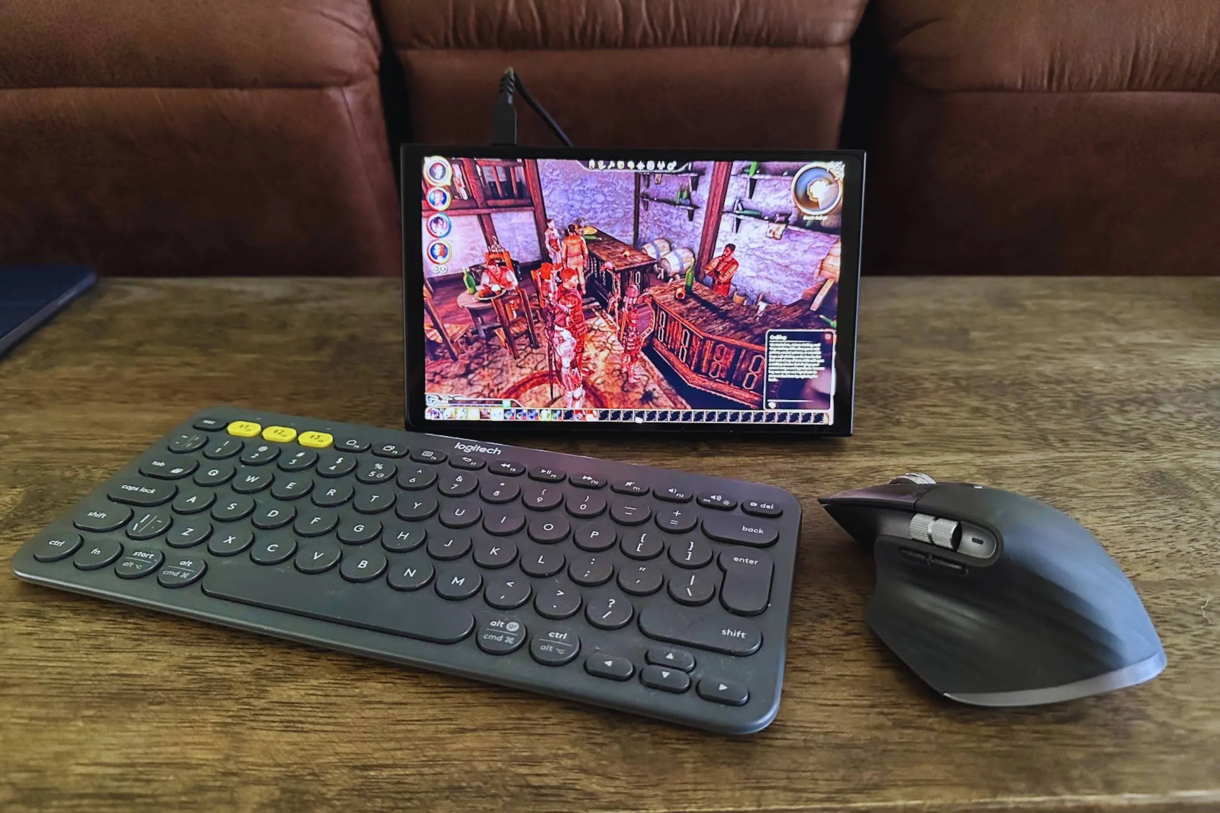 Bộ bàn phím Logitech K380 và chuột MX Master 3S, cùng thiết bị chơi game cầm tay Lenovo Legion Go đặt trên bàn gỗ, minh họa phụ kiện chơi game console.