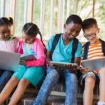 Bốn em học sinh đang sử dụng máy tính xách tay được quyên góp cho mục đích học tập.