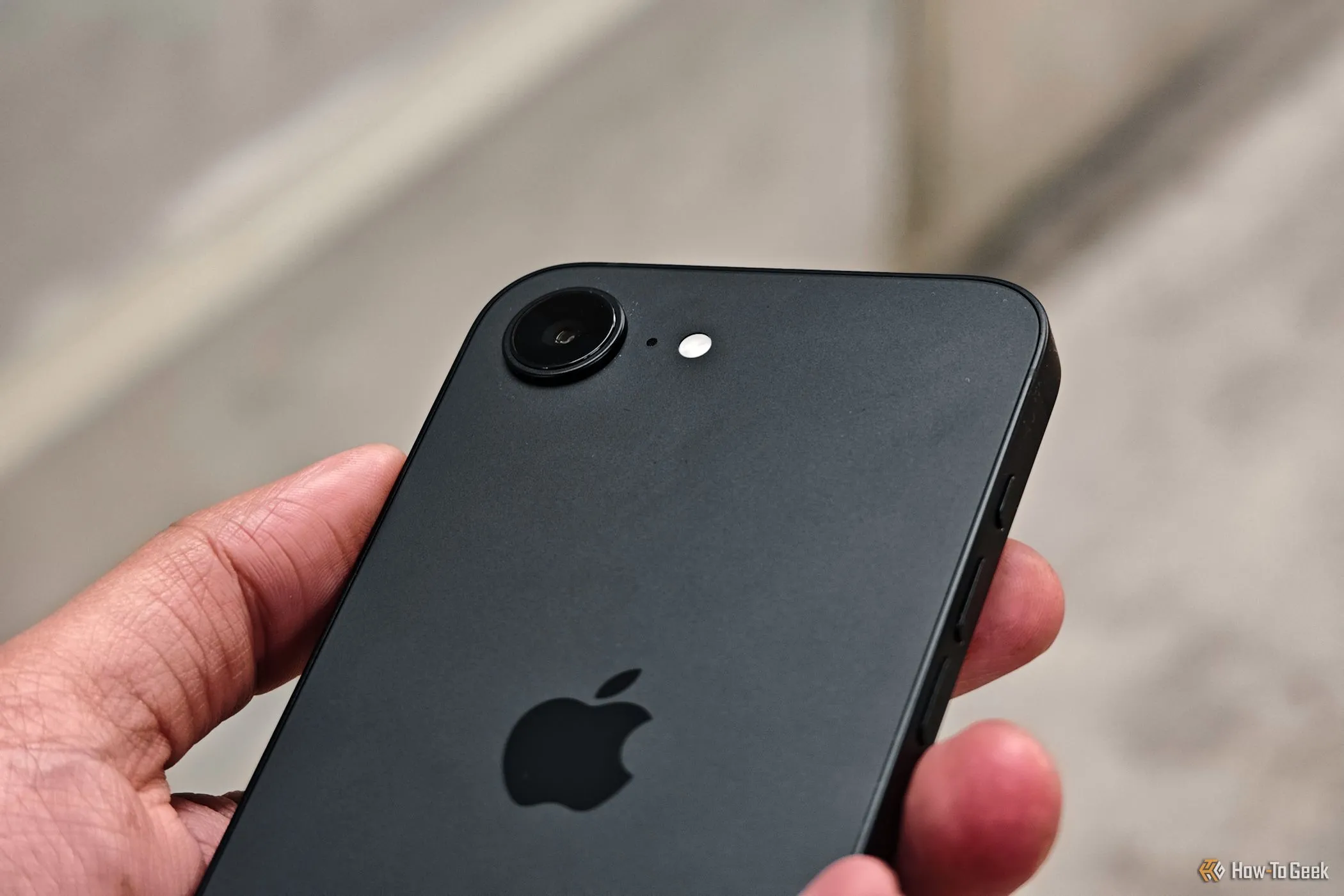 Cận cảnh bàn tay cầm điện thoại iPhone 16e hiển thị chi tiết cụm camera sau