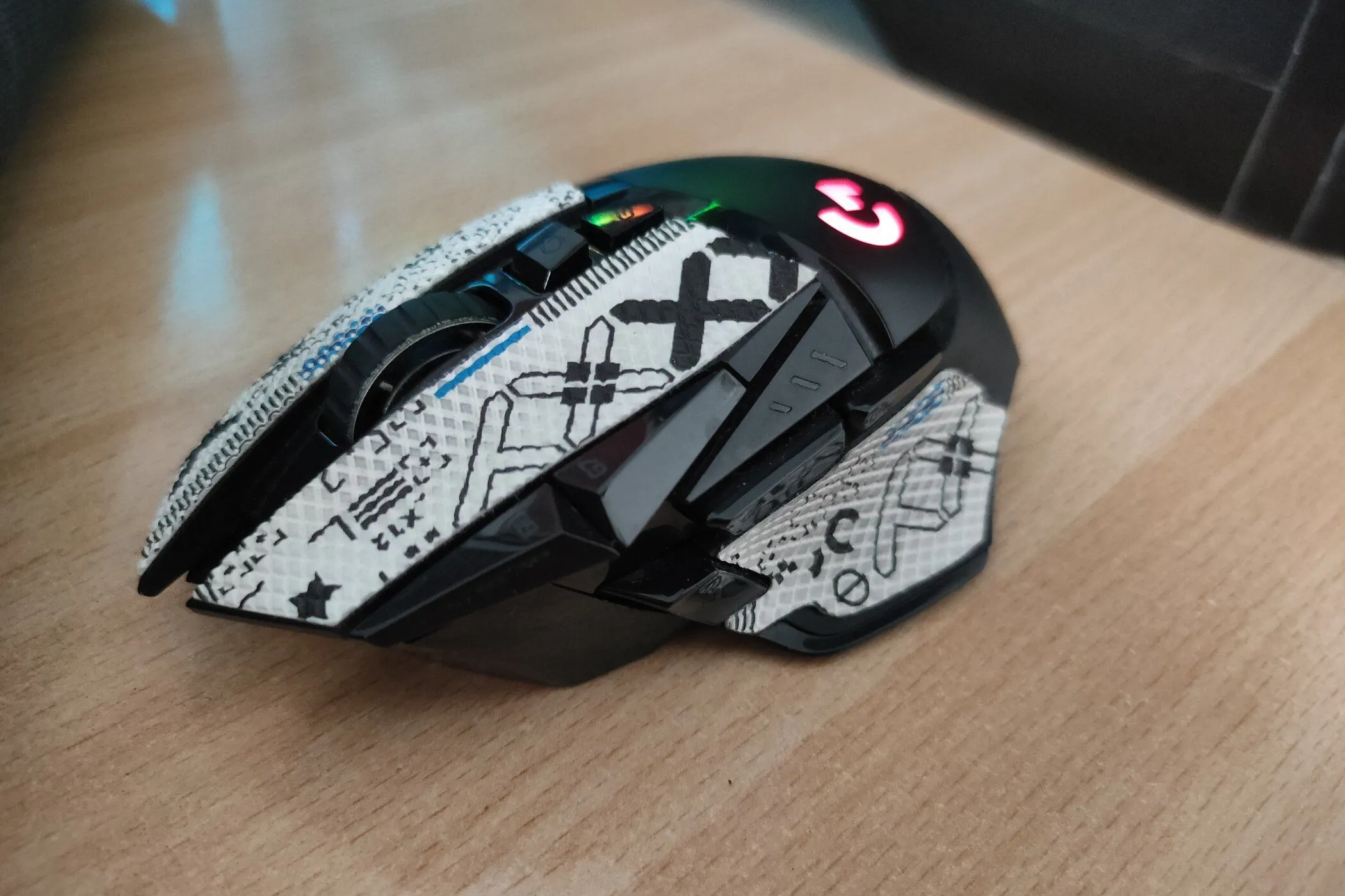 Chuột gaming Logitech G502 Lightspeed không dây đặt trên bàn gỗ, có thể dán grip tape để tăng độ bám.