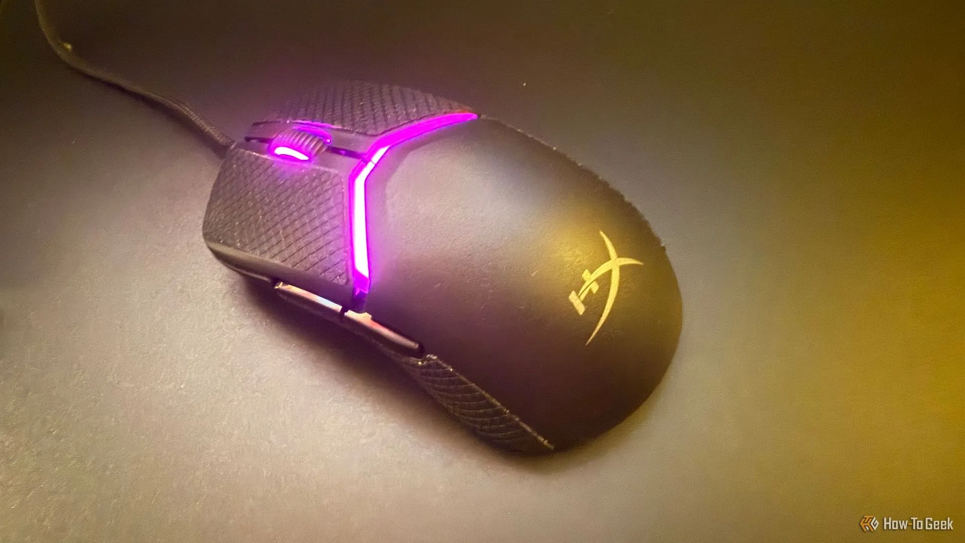 Chuột HyperX Pulsefire Saga trên bàn di chuột thủy tinh, thể hiện dây cáp linh hoạt