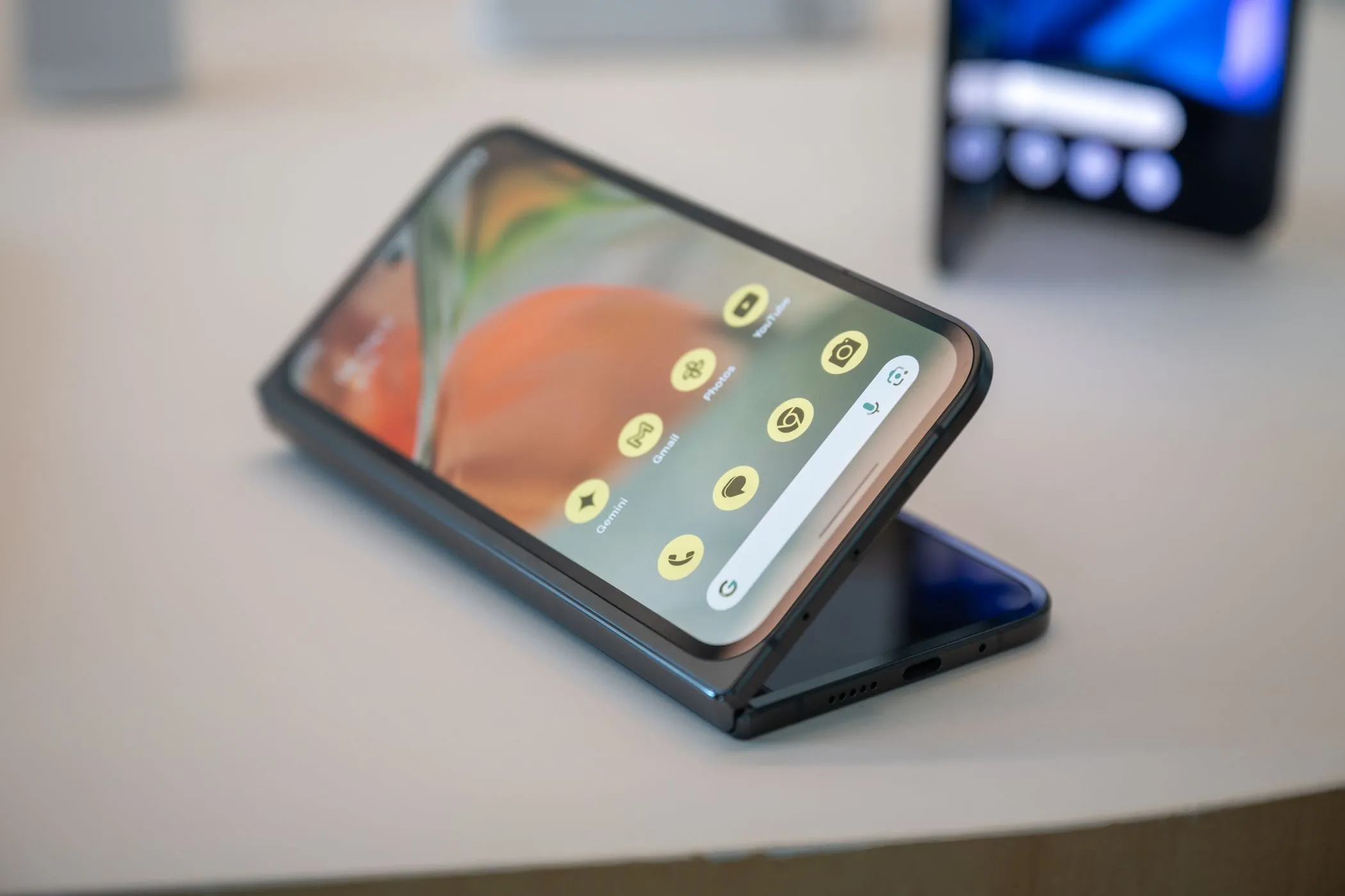 Điện thoại Google Pixel 9 Pro Fold màu đen đang đặt trên bàn trong trạng thái mở một phần, minh họa thiết kế bản lề
