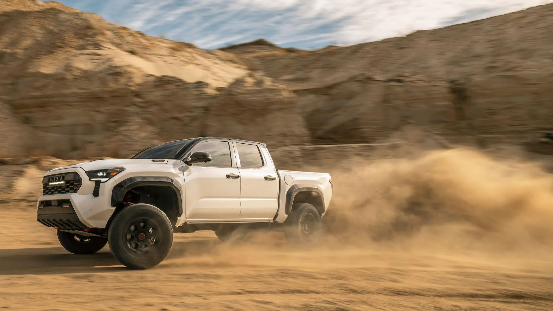 Mẫu xe bán tải Toyota TRD Pro 2025 màu xanh rêu, đang di chuyển trên địa hình gồ ghề, cho thấy khả năng off-road và sự thành công trong doanh số của các mẫu xe bán tải Toyota.