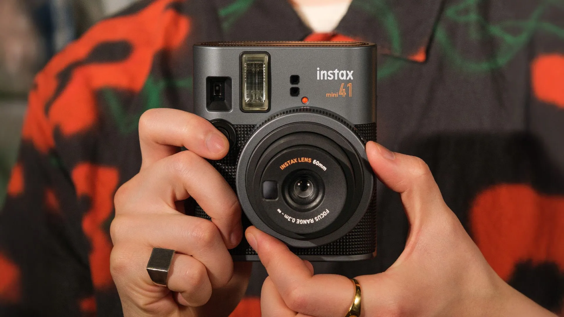Máy ảnh chụp lấy liền Fujifilm Instax Mini 41 màu xanh lá cây đặt trên bề mặt, nổi bật với thiết kế nhỏ gọn và khả năng in ảnh nhanh chóng.