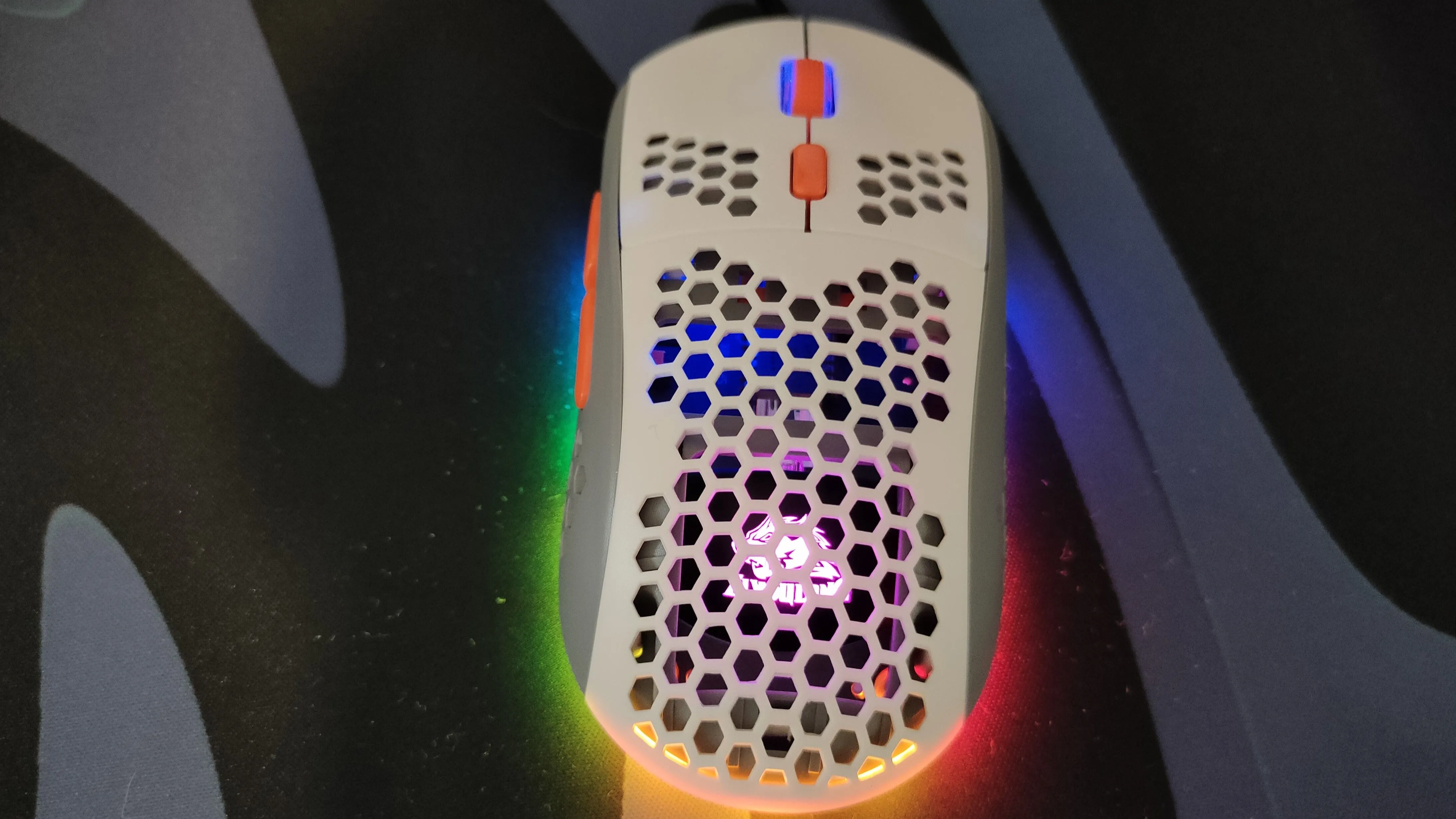 Một mẫu chuột gaming siêu nhẹ màu trắng với thiết kế đục lỗ và đèn RGB, minh họa cho việc giảm trọng lượng chuột.