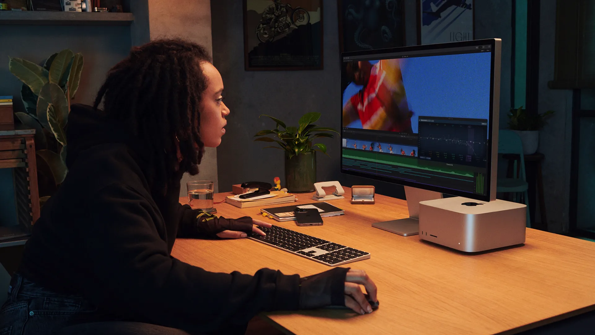 Một nghệ sĩ đang sử dụng Mac Studio với Studio Display, minh họa việc thiết bị nhỏ gọn vừa vặn dưới màn hình.