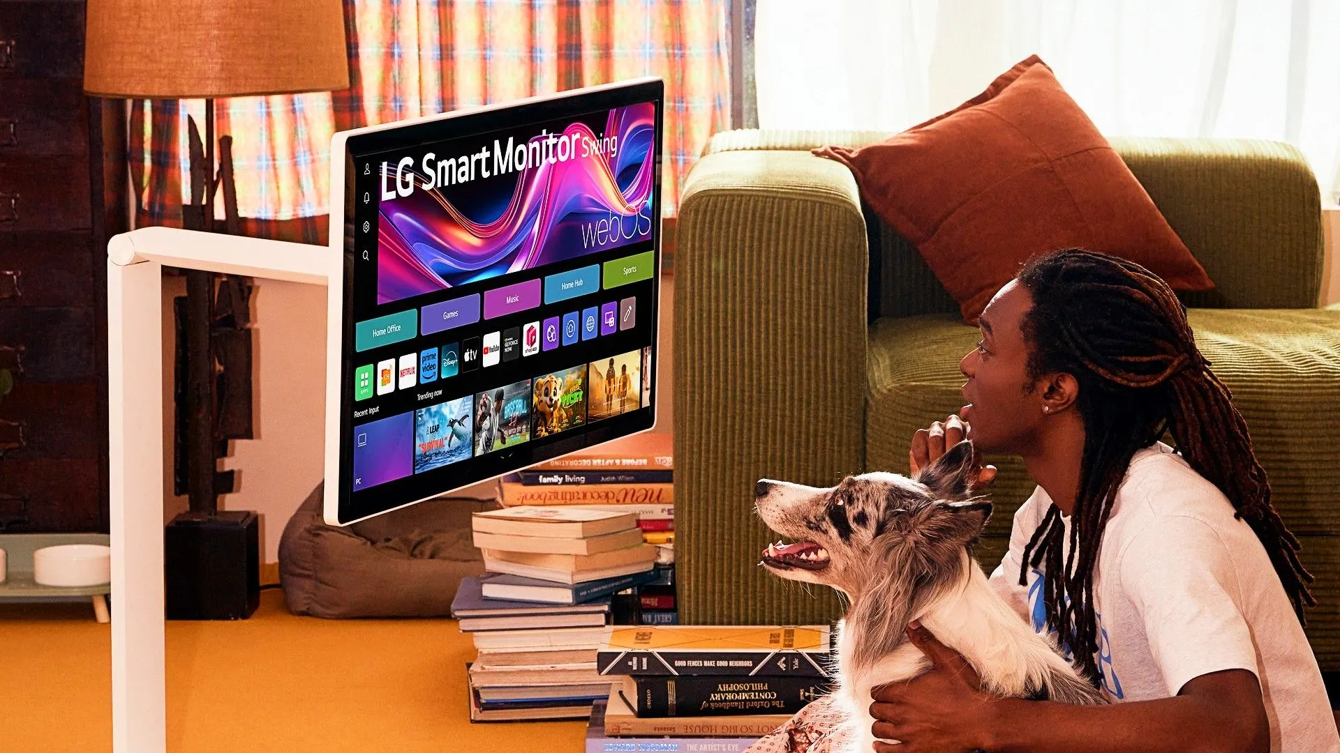 Một người đàn ông và chú chó đang sử dụng màn hình LG Smart Monitor Swing trên sàn nhà