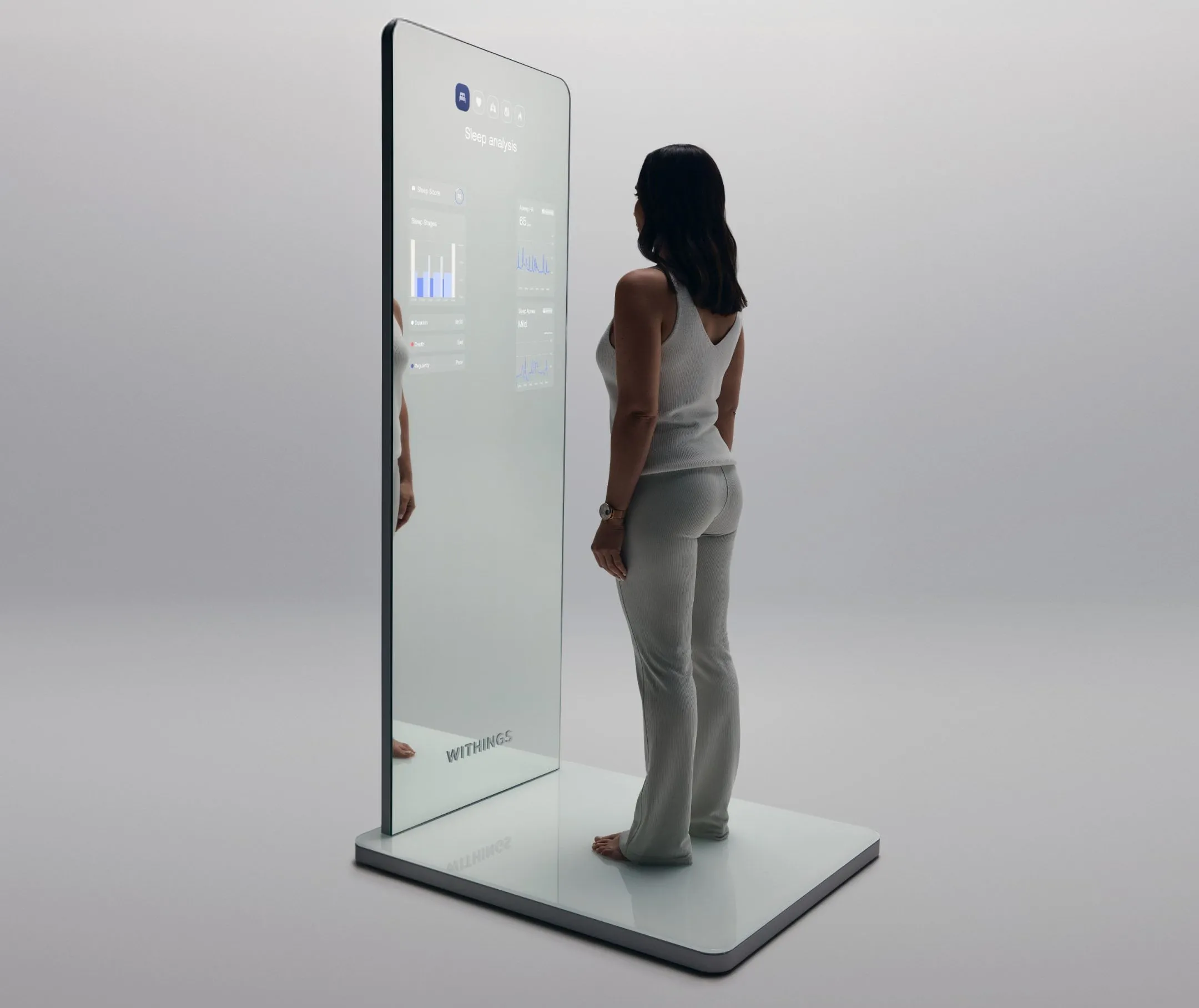Người phụ nữ đứng trên đế của Withings Omnia, theo dõi các chỉ số sức khỏe hiển thị trên gương toàn thân.