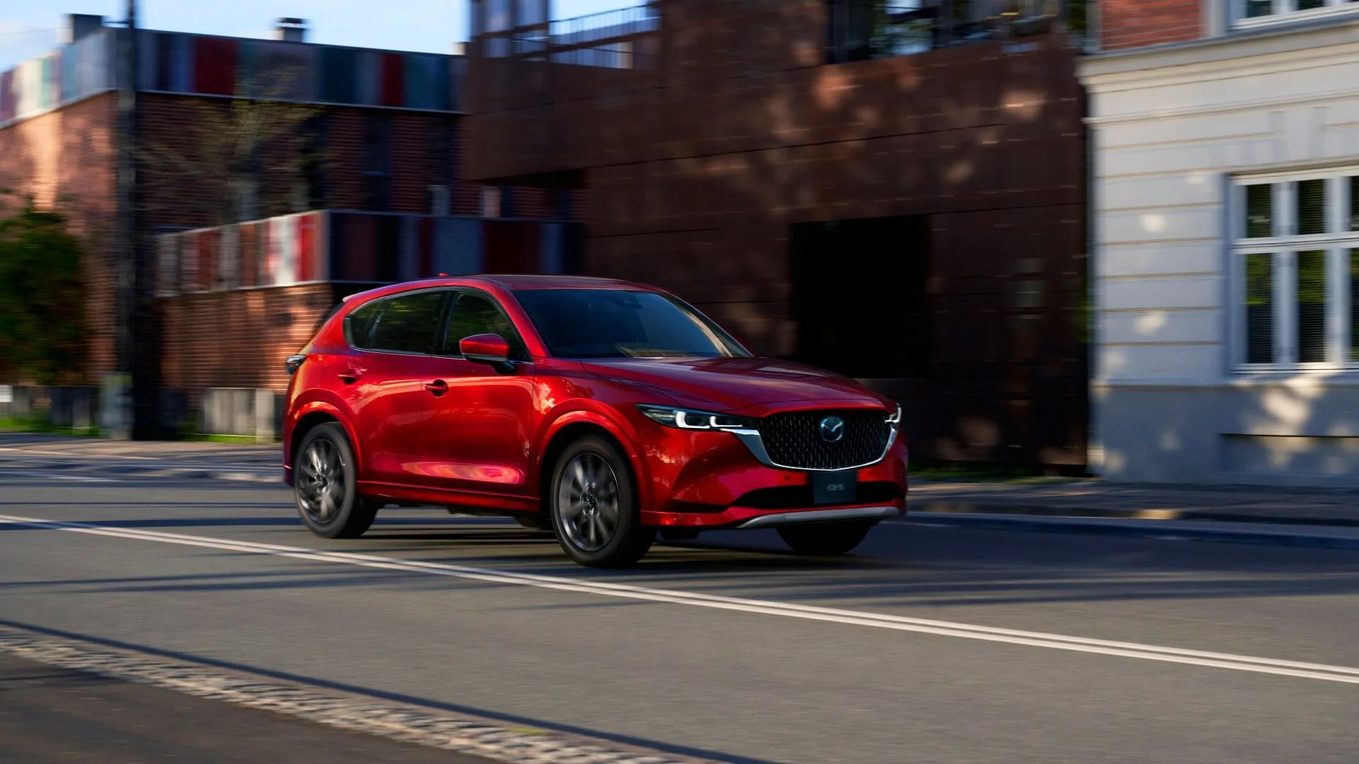 Phần đầu xe Mazda CX-5 thế hệ mới màu đỏ ánh kim, với lưới tản nhiệt lớn và đèn pha sắc nét.